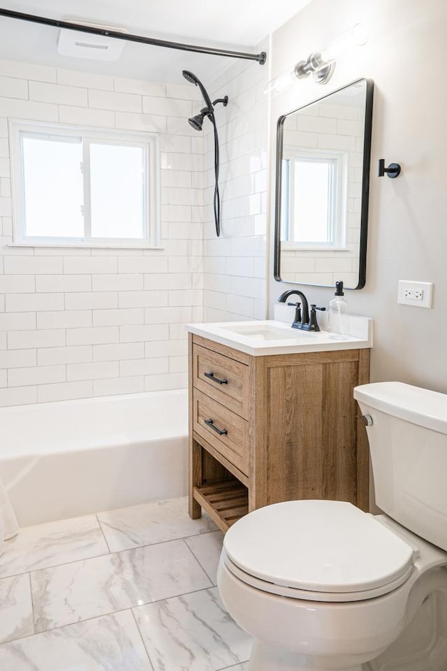 full bathroom featuring tiled shower / bath, vanity, and toilet