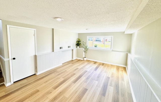 spare room featuring a textured ceiling and light wood-type flooring