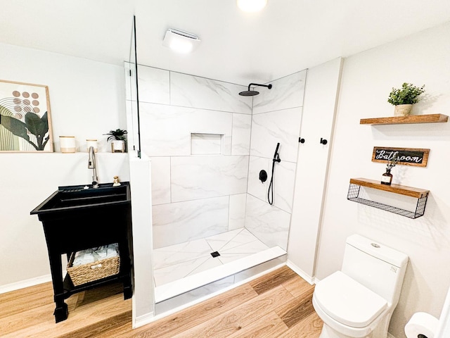 bathroom with a tile shower and toilet