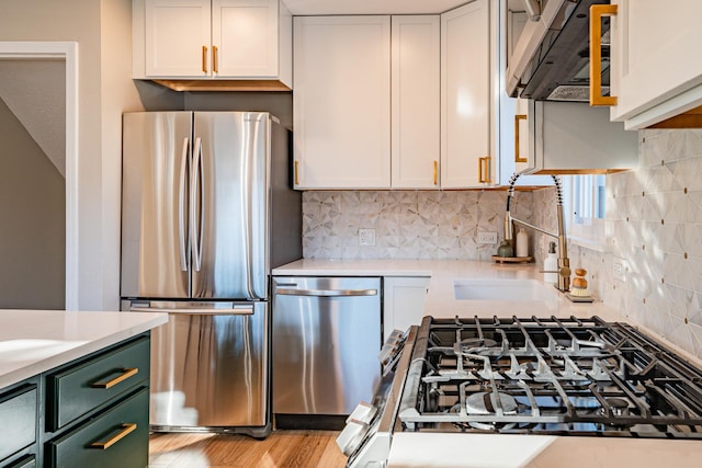 kitchen featuring light hardwood / wood-style flooring, tasteful backsplash, range hood, appliances with stainless steel finishes, and white cabinetry