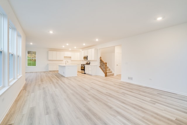 unfurnished living room featuring sink and light wood-type flooring