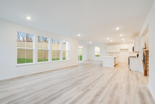 unfurnished living room featuring sink and light hardwood / wood-style floors