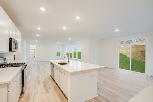 kitchen featuring white cabinets, stainless steel appliances, a kitchen island with sink, and sink