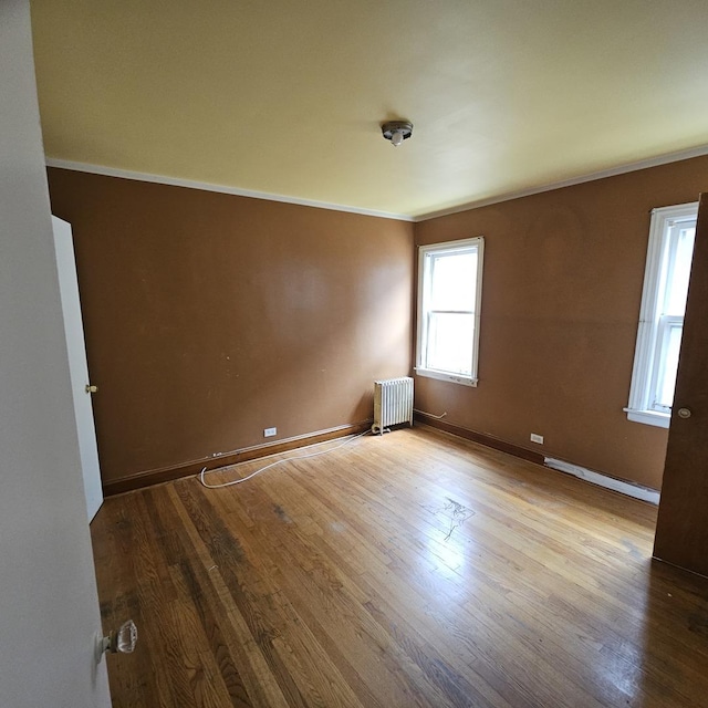 spare room with radiator heating unit, light hardwood / wood-style flooring, and crown molding