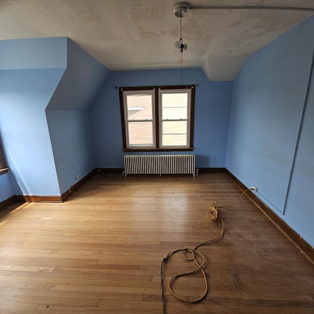 bonus room featuring radiator heating unit, light hardwood / wood-style floors, and lofted ceiling