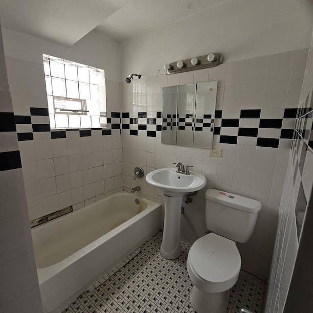 bathroom featuring tiled shower / bath combo, toilet, and tile walls