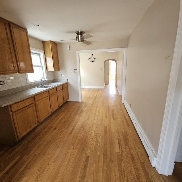 kitchen with decorative backsplash, sink, ceiling fan, and light hardwood / wood-style floors