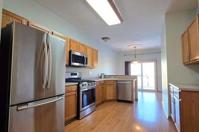 kitchen with light hardwood / wood-style floors, kitchen peninsula, hanging light fixtures, and appliances with stainless steel finishes