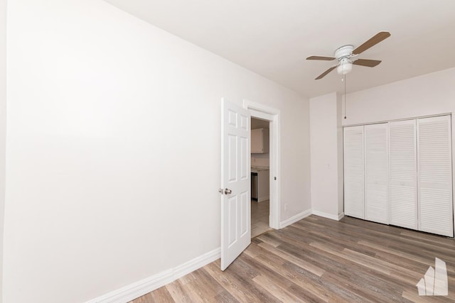 unfurnished bedroom featuring hardwood / wood-style floors, a closet, and ceiling fan