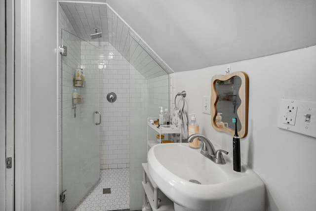 bathroom with tile patterned floors, vaulted ceiling, a shower with shower door, and sink