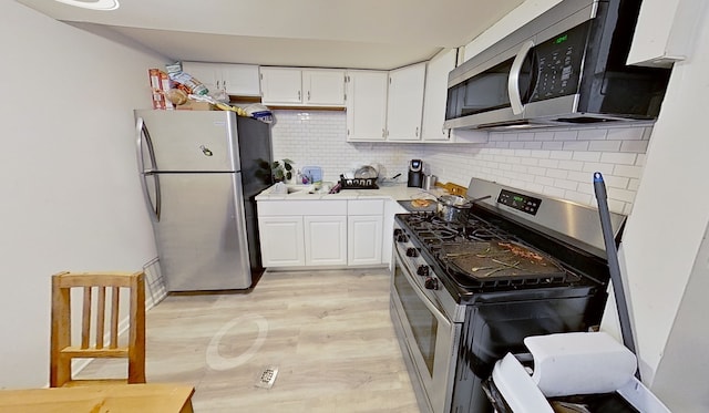 kitchen featuring decorative backsplash, white cabinetry, and appliances with stainless steel finishes