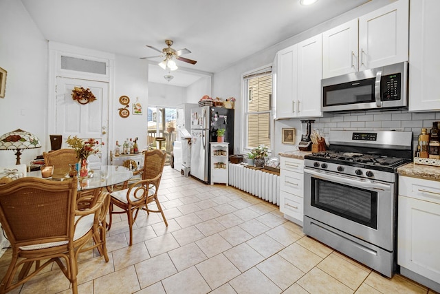 kitchen featuring decorative backsplash, white cabinets, light tile patterned floors, and appliances with stainless steel finishes