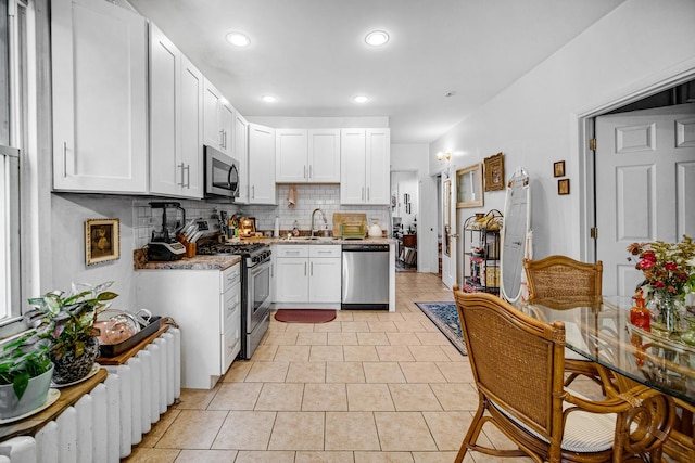 kitchen with white cabinets, appliances with stainless steel finishes, tasteful backsplash, and sink