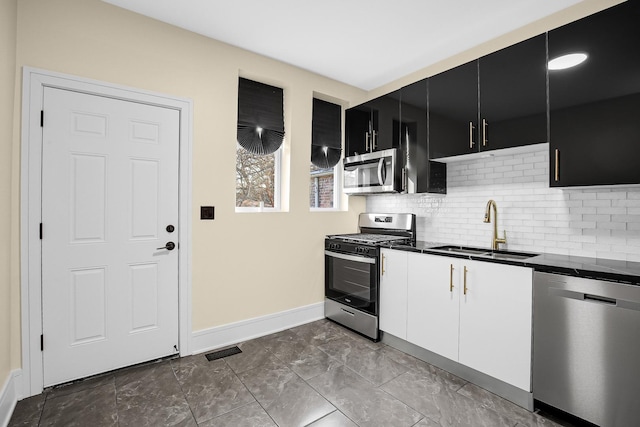 kitchen with decorative backsplash, appliances with stainless steel finishes, white cabinetry, and sink