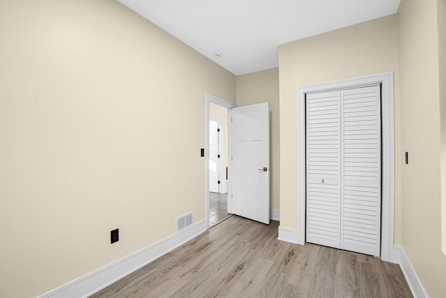 unfurnished bedroom featuring light hardwood / wood-style flooring and a closet