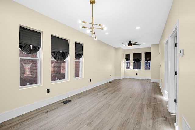 unfurnished room featuring ceiling fan with notable chandelier and light hardwood / wood-style floors