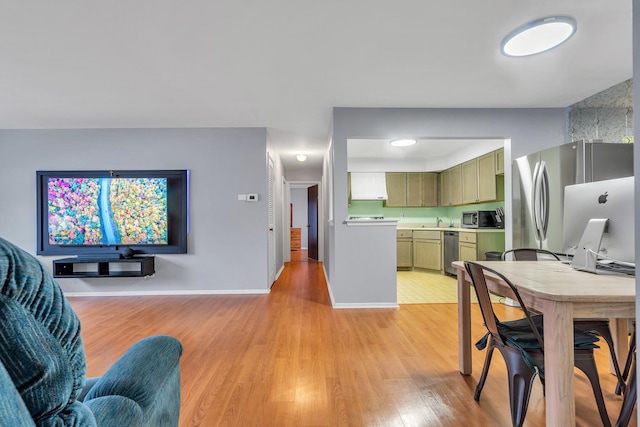 kitchen featuring sink, appliances with stainless steel finishes, light hardwood / wood-style floors, and green cabinetry