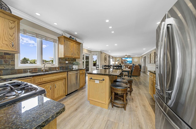 kitchen with appliances with stainless steel finishes, a kitchen breakfast bar, tasteful backsplash, light hardwood / wood-style flooring, and a center island