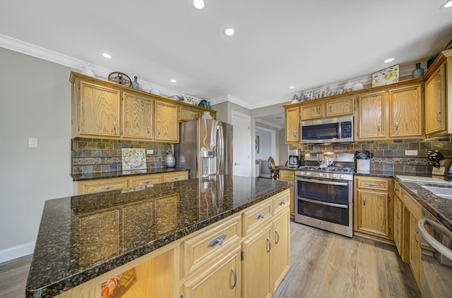 kitchen with appliances with stainless steel finishes, tasteful backsplash, light hardwood / wood-style flooring, and a kitchen island