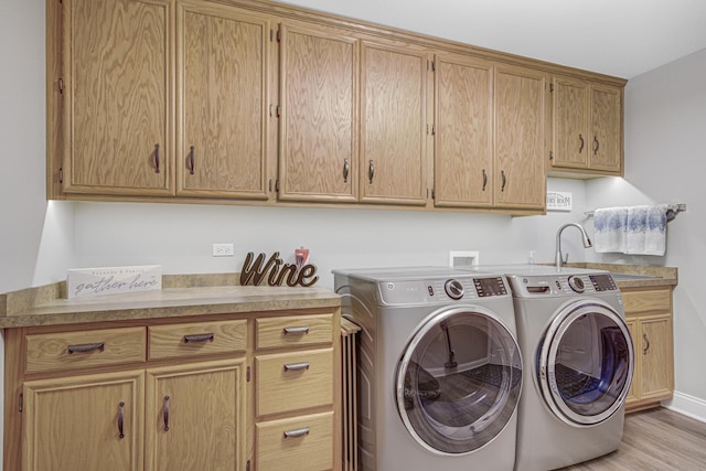 washroom with sink, washer and clothes dryer, cabinets, and light hardwood / wood-style flooring