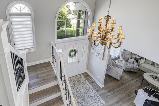 foyer entrance with dark wood-type flooring, a chandelier, and a high ceiling