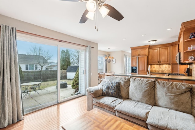 living room featuring ceiling fan with notable chandelier and light hardwood / wood-style flooring