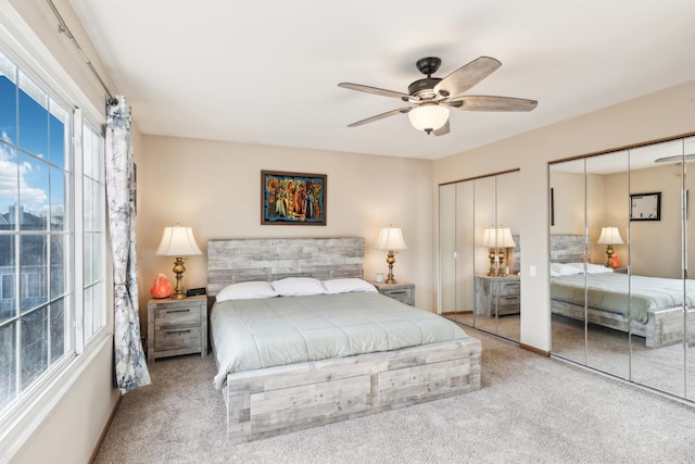 carpeted bedroom with ceiling fan and two closets