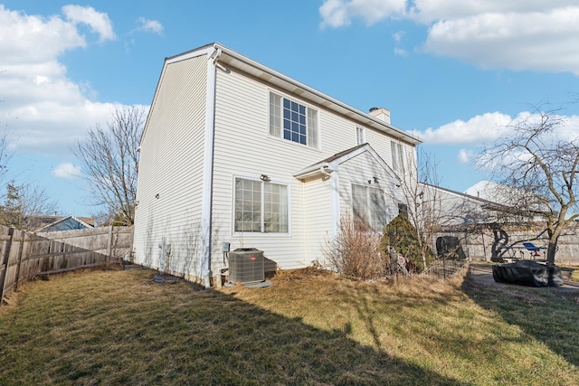 back of property with central AC and a lawn