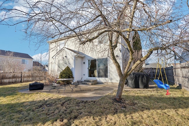 rear view of property featuring a playground, a lawn, and a patio area