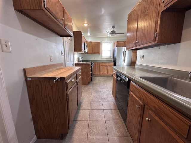 kitchen featuring stainless steel appliances, ceiling fan, sink, light tile patterned floors, and butcher block countertops