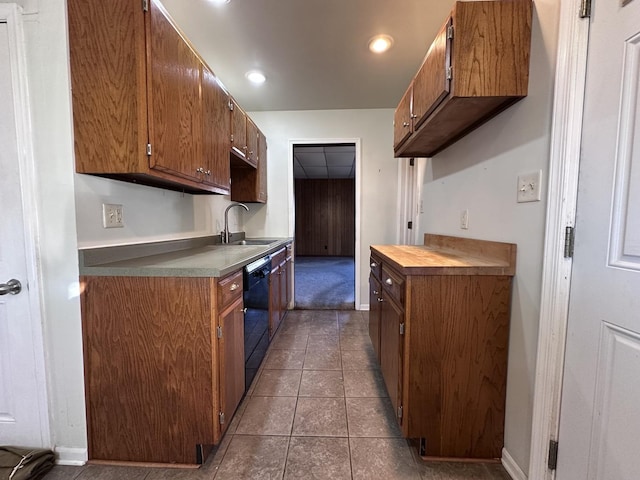 kitchen with black dishwasher, dark tile patterned floors, and sink