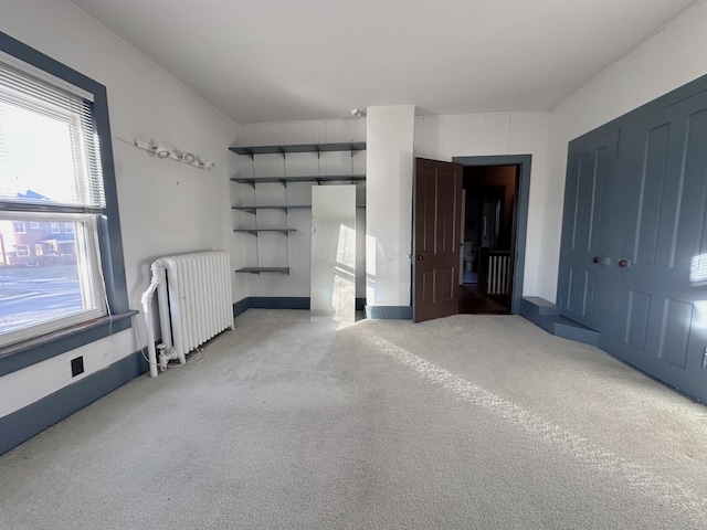 unfurnished bedroom featuring radiator, light carpet, and a closet