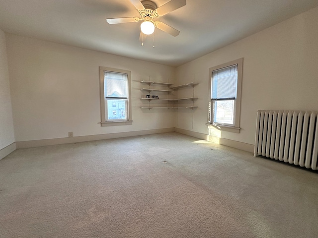 spare room with radiator heating unit, light colored carpet, and ceiling fan