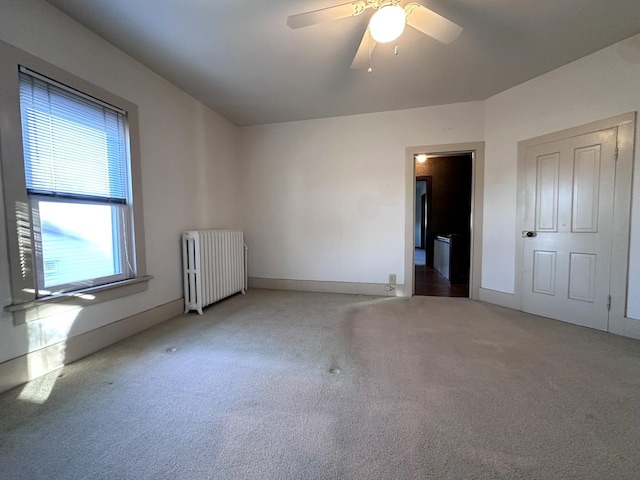 unfurnished room with carpet flooring, ceiling fan, and radiator heating unit