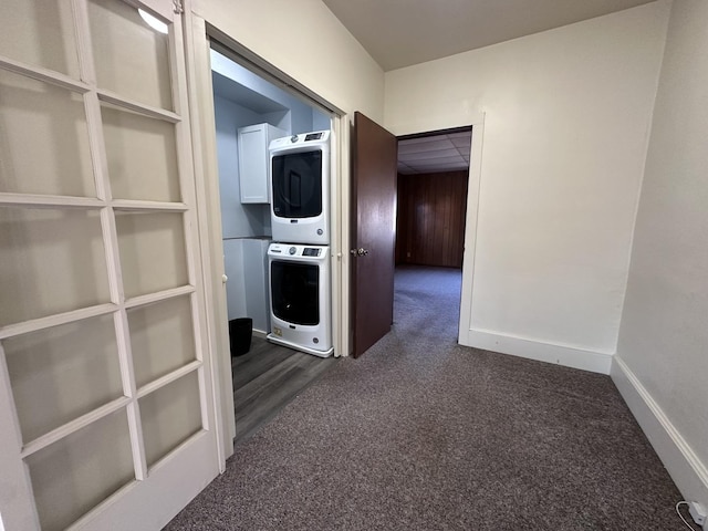 hall featuring dark carpet and stacked washer / drying machine