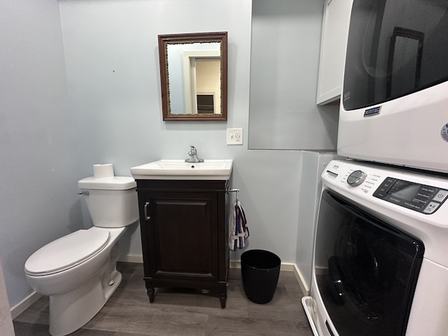 bathroom featuring vanity, toilet, wood-type flooring, and stacked washer and dryer