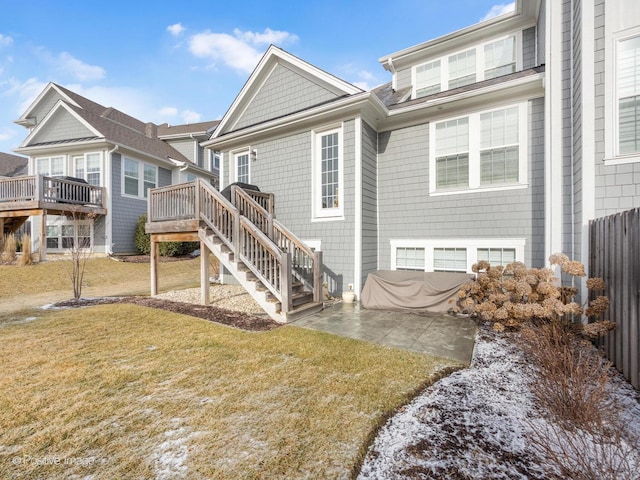 back of property with a wooden deck, a patio area, and a lawn