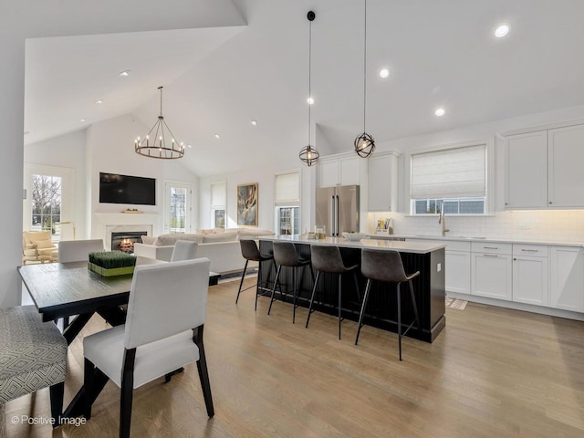 dining space with sink, light hardwood / wood-style floors, a chandelier, and high vaulted ceiling