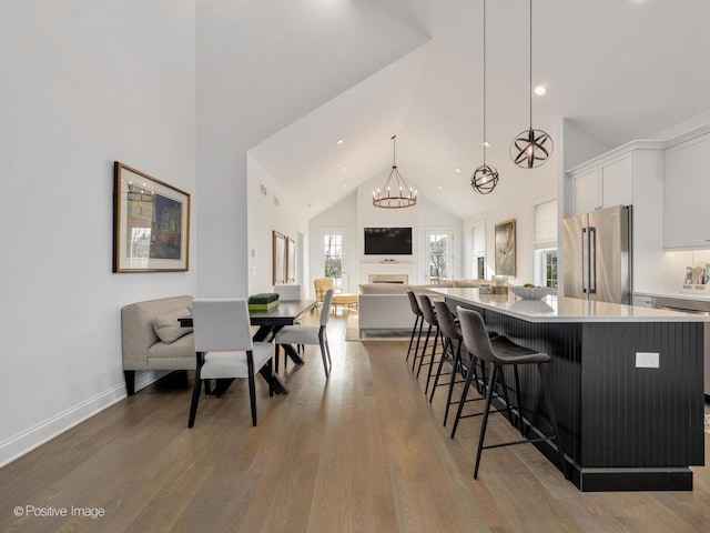 kitchen featuring decorative light fixtures, white cabinetry, high end refrigerator, hardwood / wood-style flooring, and a large island