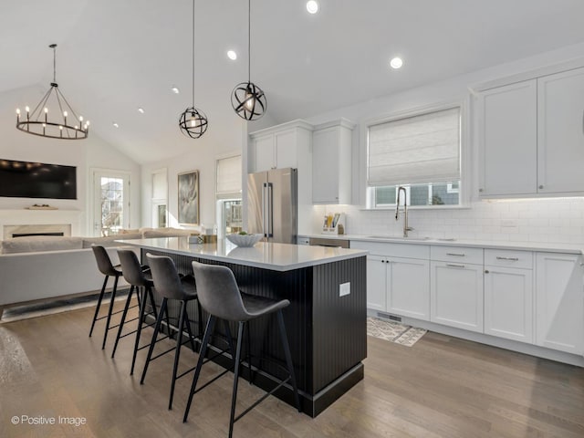 kitchen featuring decorative light fixtures, high end refrigerator, white cabinets, and a kitchen island