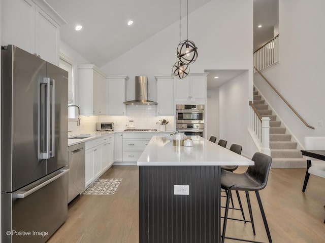 kitchen featuring white cabinets, appliances with stainless steel finishes, sink, and wall chimney range hood