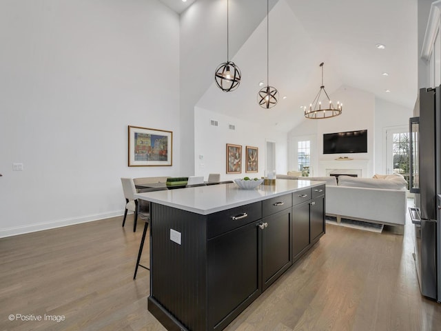 kitchen with high end fridge, a center island, hanging light fixtures, light wood-type flooring, and a kitchen breakfast bar