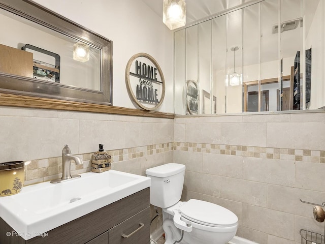 bathroom with vanity, tile walls, and toilet