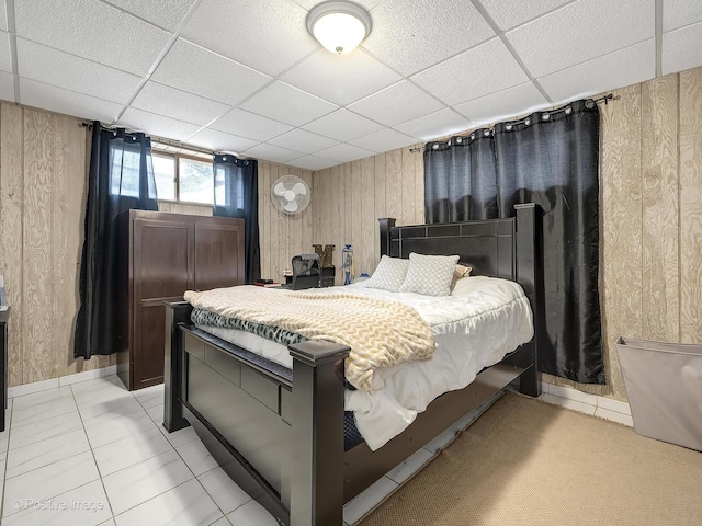 bedroom with a paneled ceiling and wooden walls