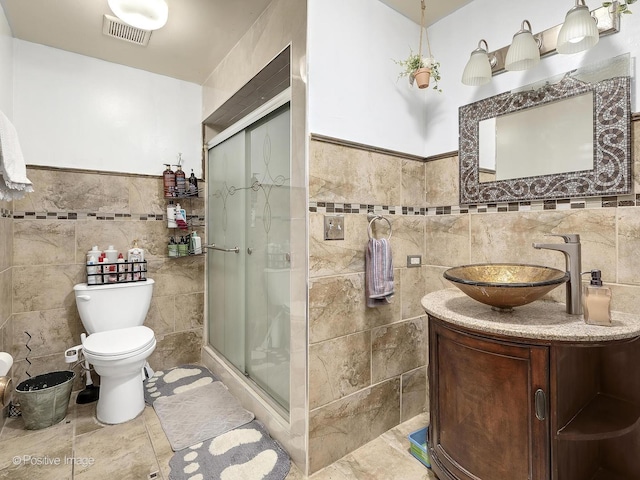 bathroom with vanity, toilet, an enclosed shower, and tile walls