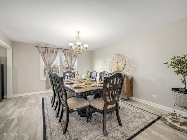 dining area with light wood-type flooring and an inviting chandelier