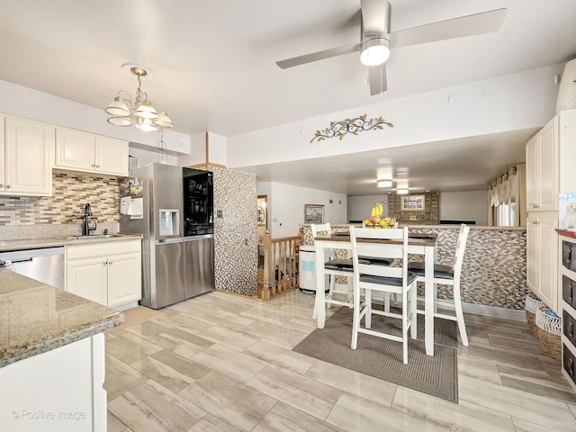 kitchen with pendant lighting, stainless steel appliances, light stone counters, and white cabinetry