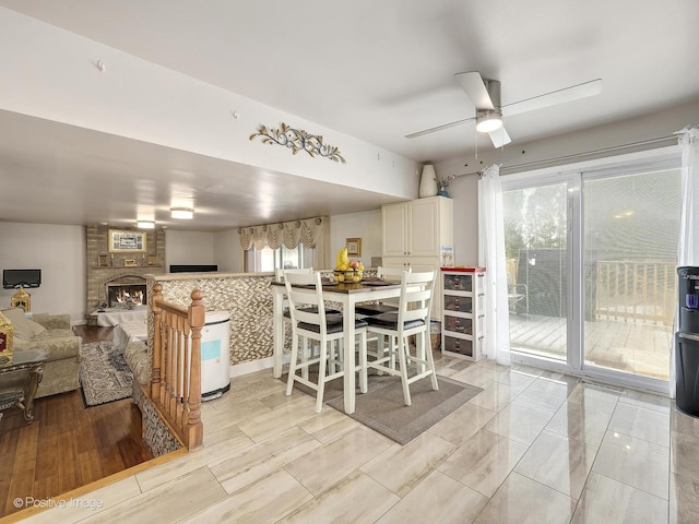 dining space with ceiling fan, a healthy amount of sunlight, and a fireplace