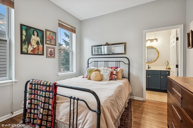 bedroom with ensuite bathroom and light wood-type flooring