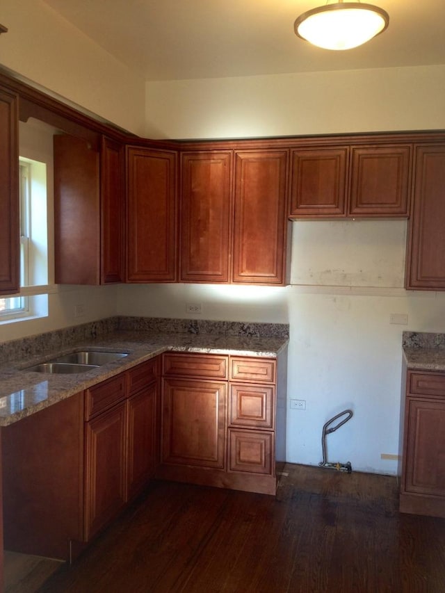 kitchen with stone countertops, sink, and dark wood-type flooring